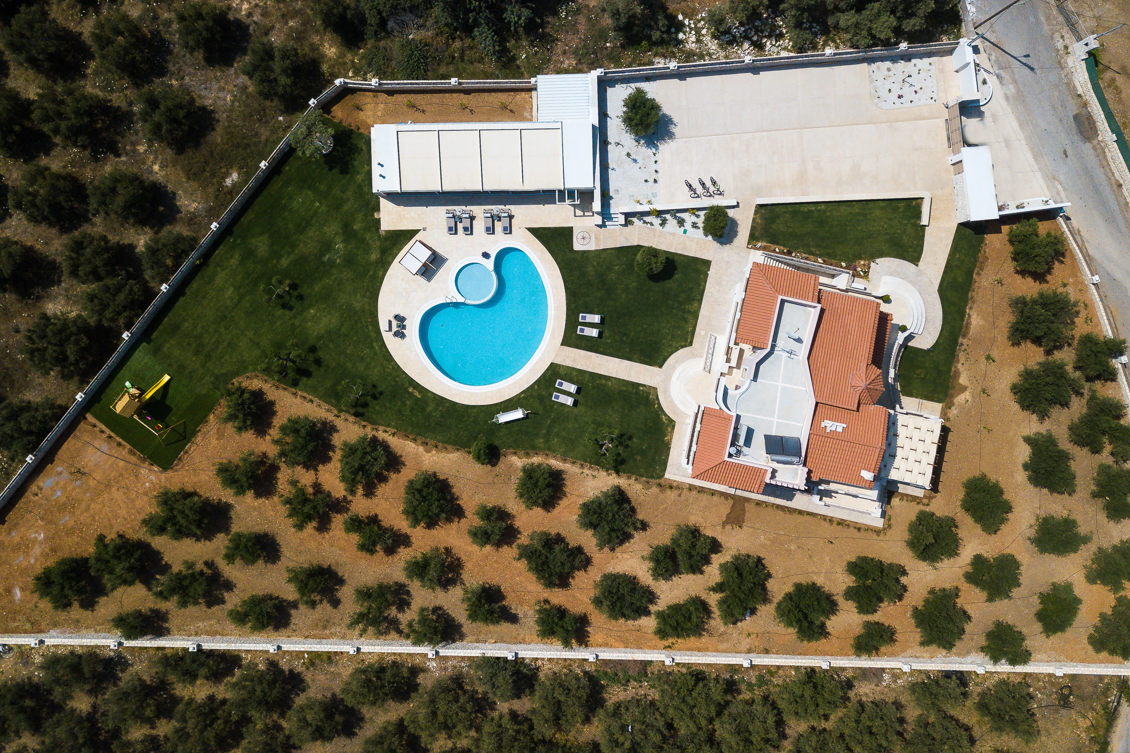 Overhead view of the walled Aelia Residence estate surrounded by rows of olive trees
