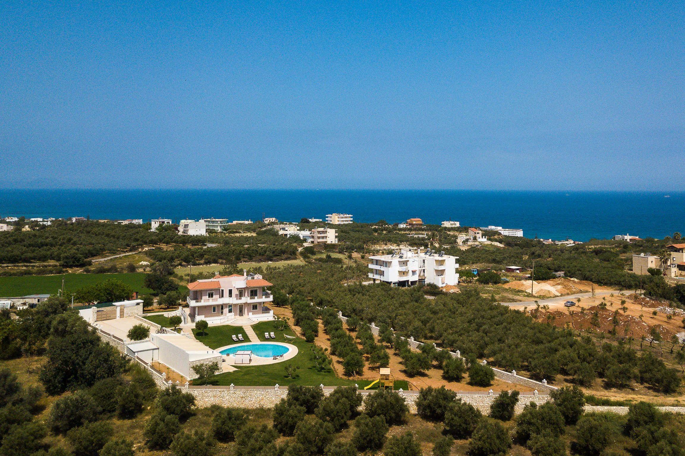 Aerial view of Aelia Residence among olive groves near the Cretan coast