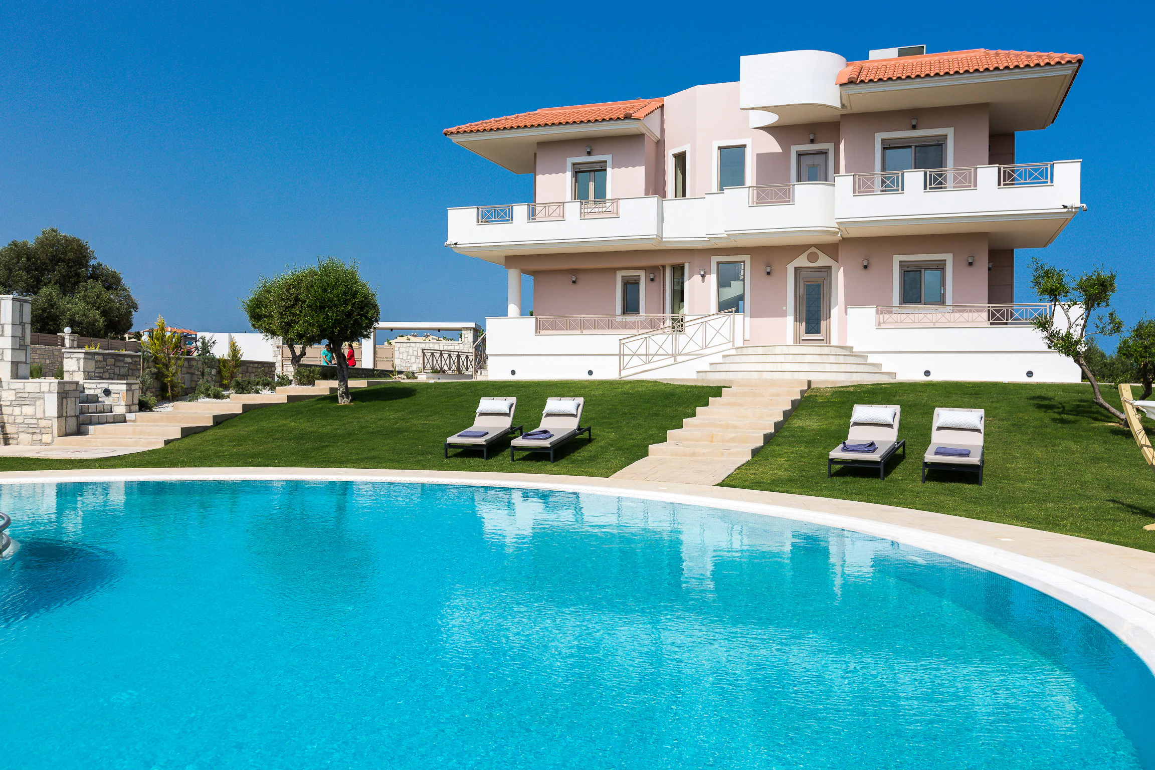 Curved private pool, lawns and Aelia Residence in daylight