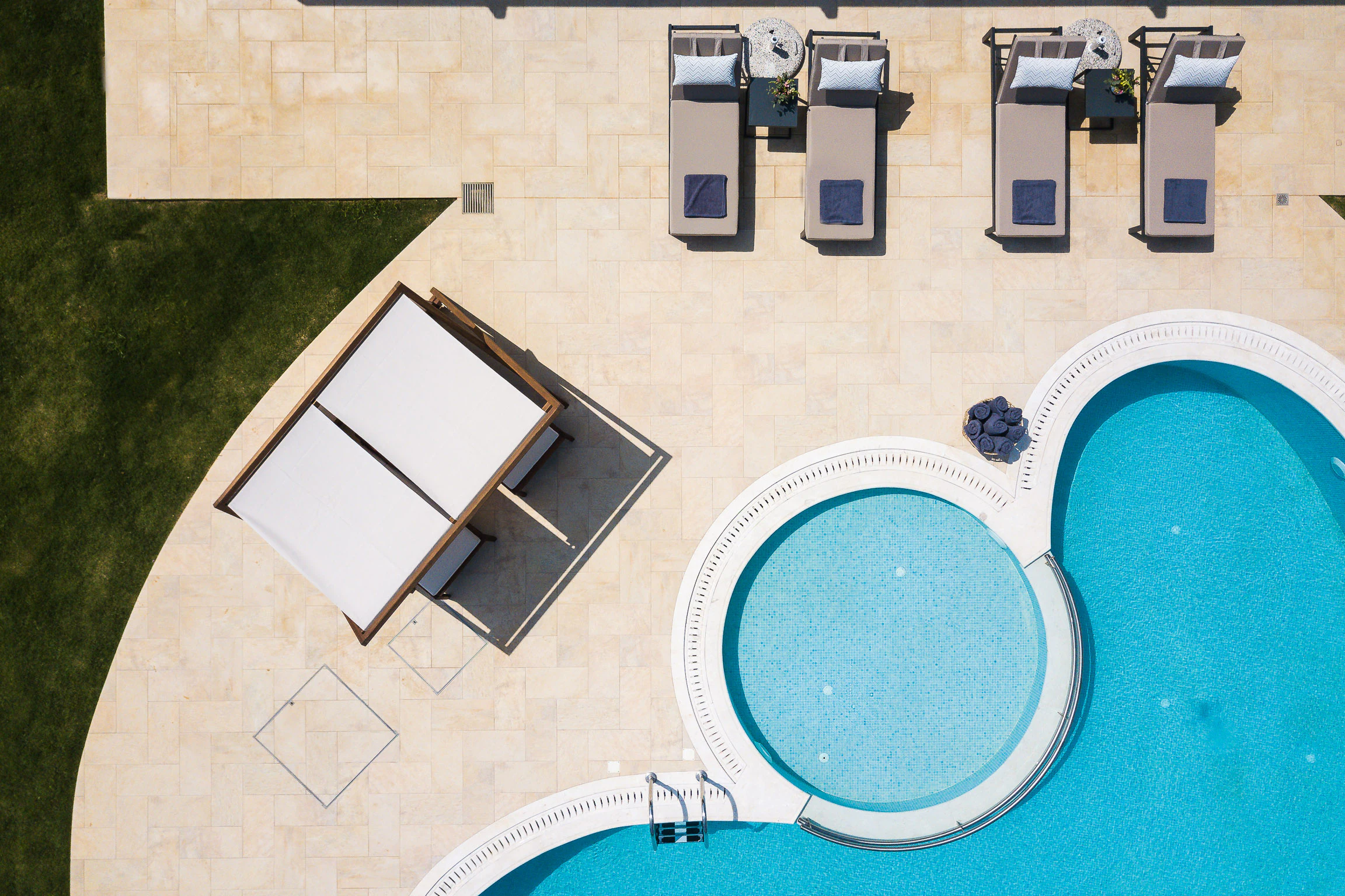 Overhead view of the main pool, the round children's pool, the shaded day bed and the poolside loungers