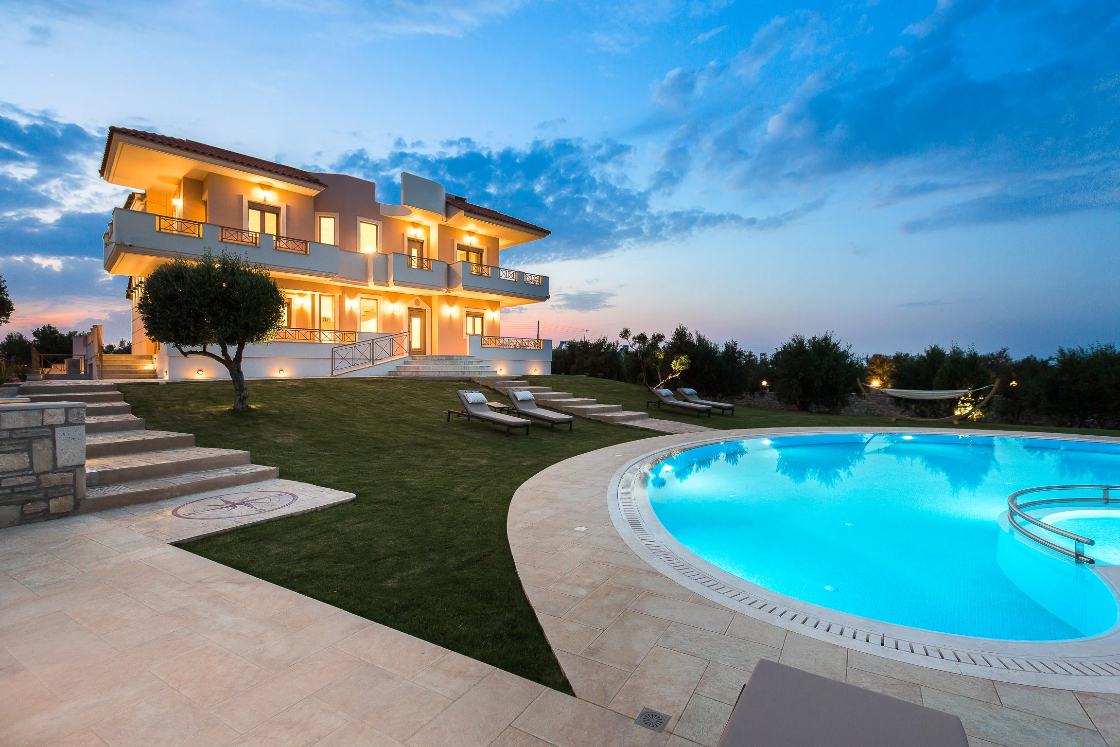 Illuminated villa and pool pavilion at dusk