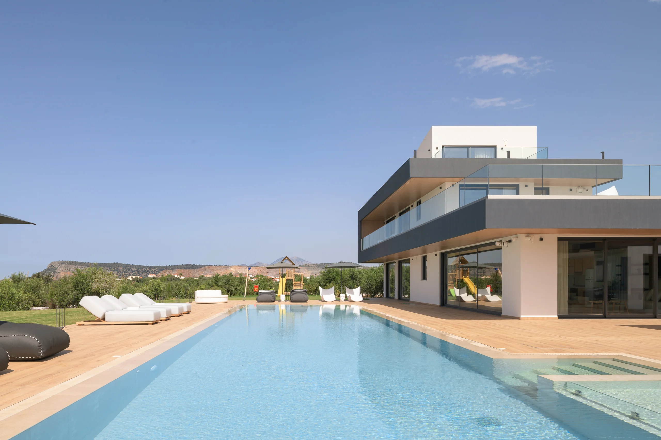 Long pool view toward the villa under a clear summer sky at Aesthea Exclusive Villa
