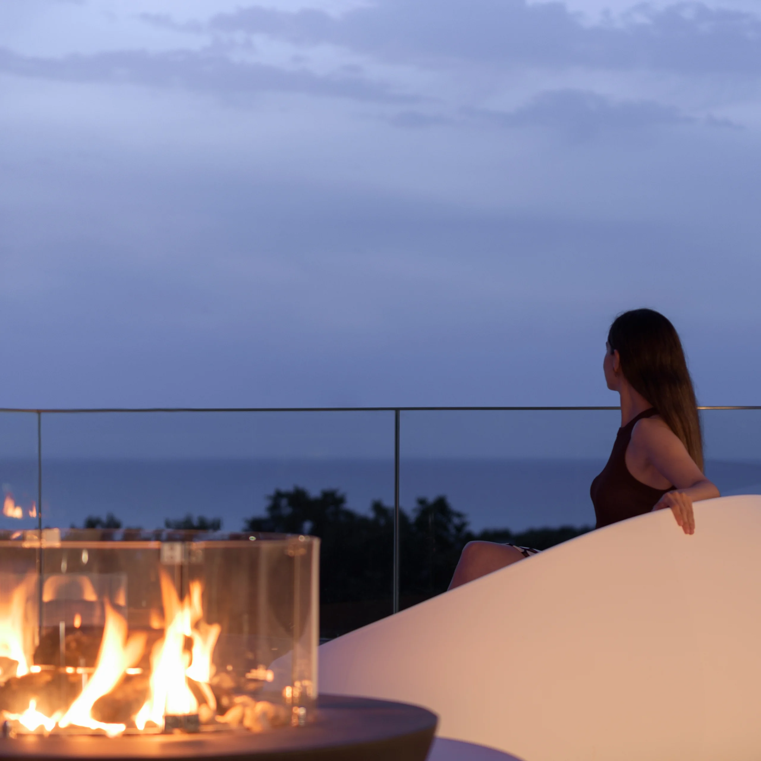 Guest seated beside the rooftop fire feature at dusk at Aesthea Exclusive Villa