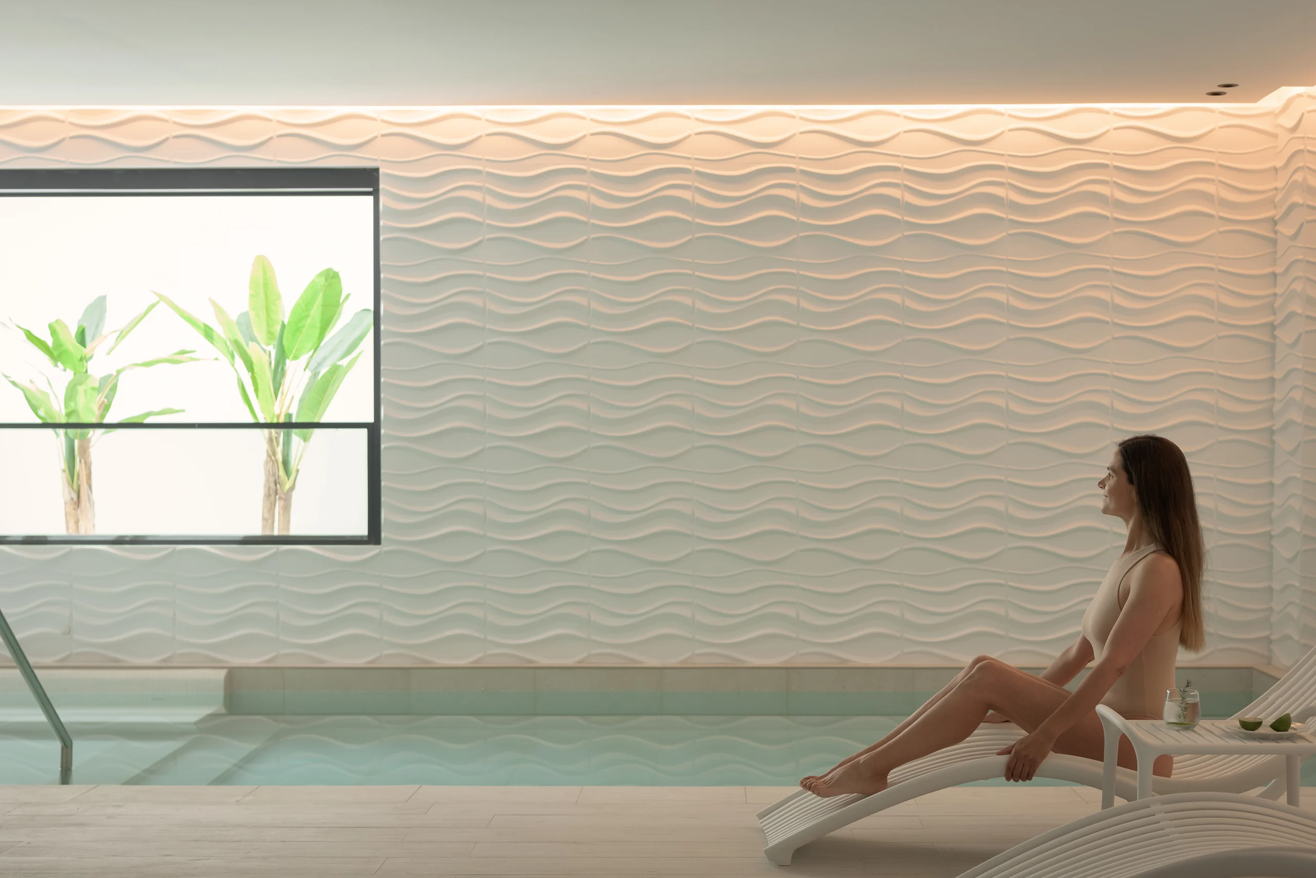 Indoor pool with loungers and planting beyond the window at Aesthea Exclusive Villa
