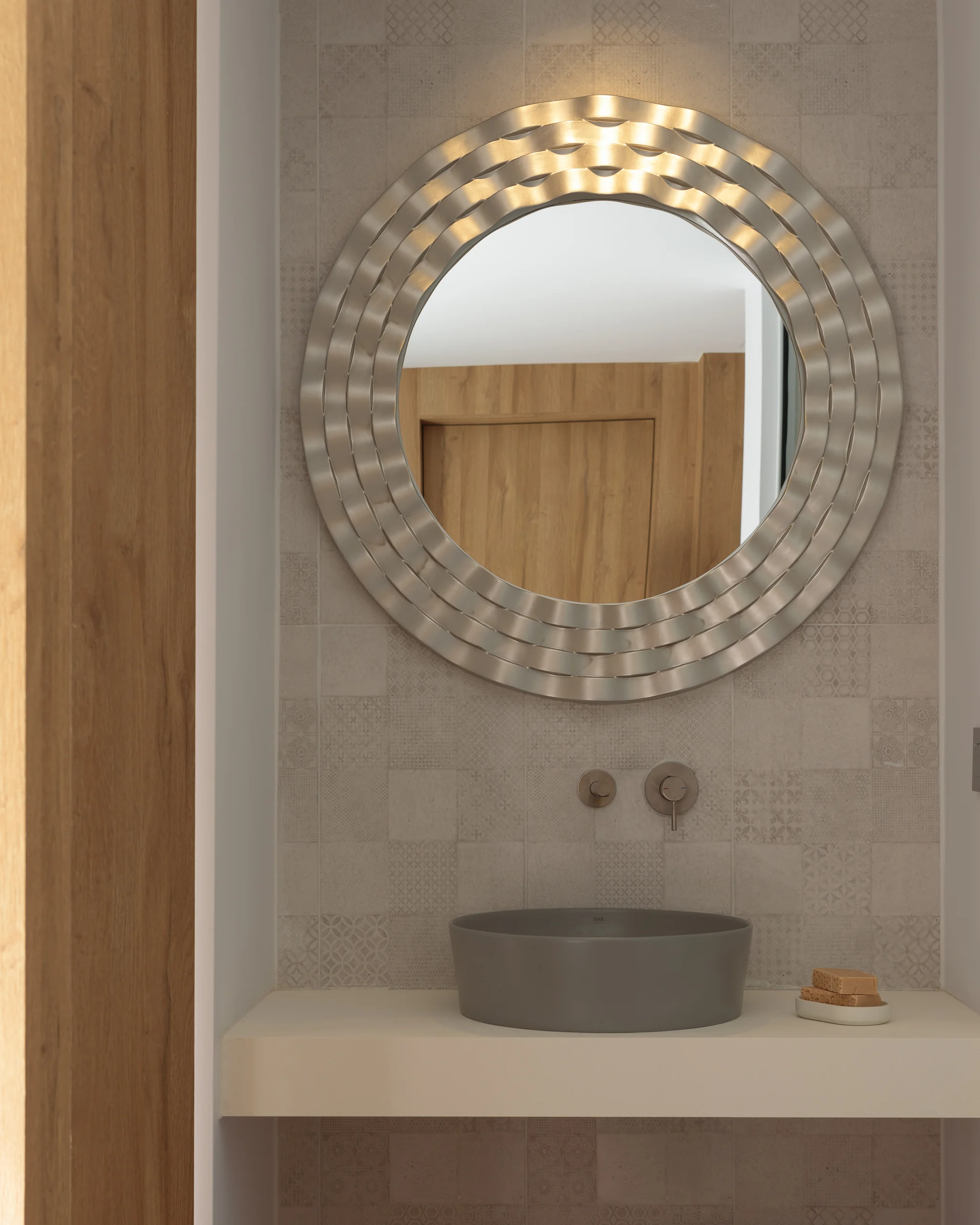 Round mirror and stone vanity in the ensuite of First-floor Bedroom 3 at Aesthea Exclusive Villa