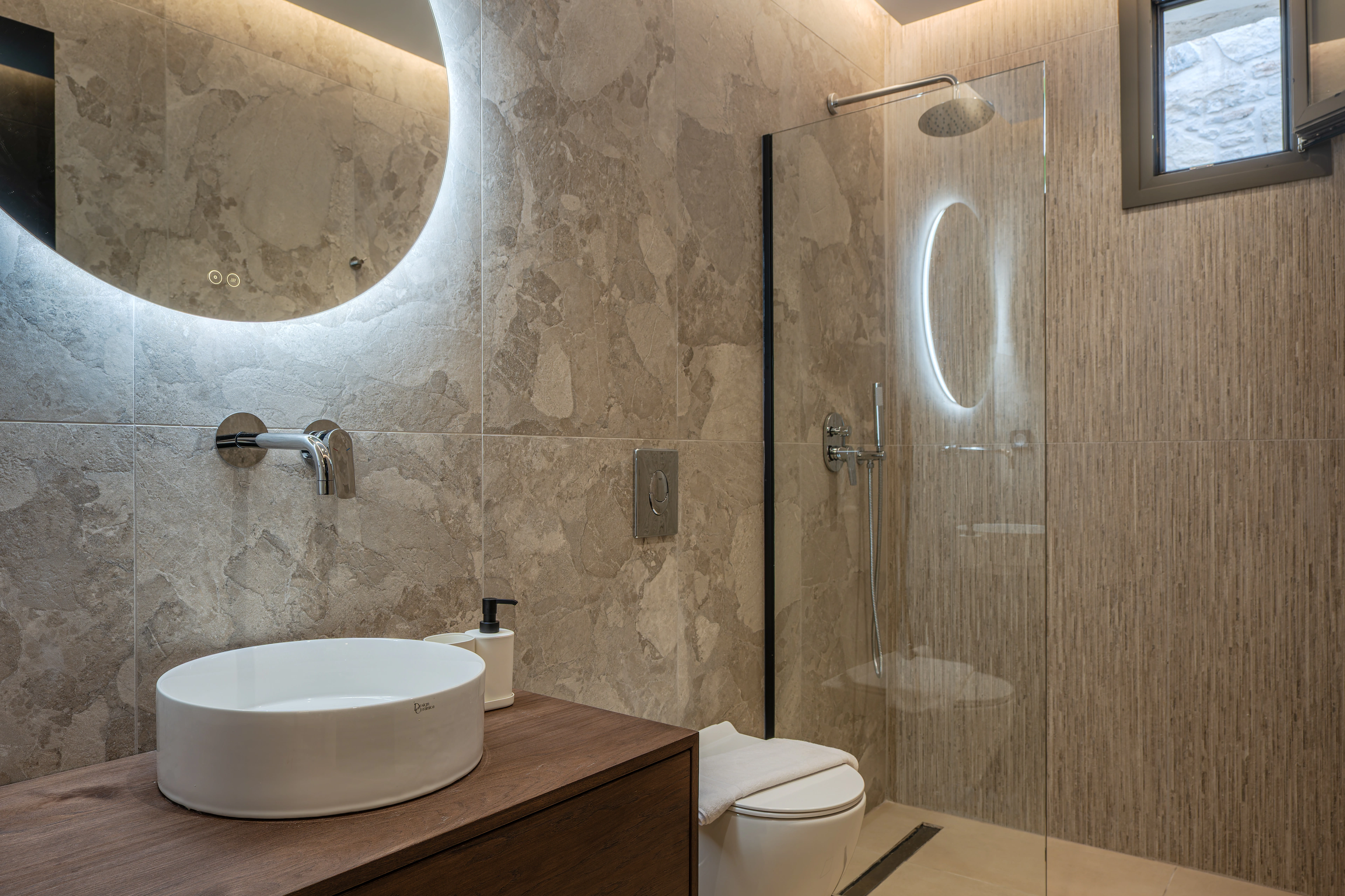 Private en-suite bathroom for Left Crete bedroom 02 with stone finishes and walk-in shower