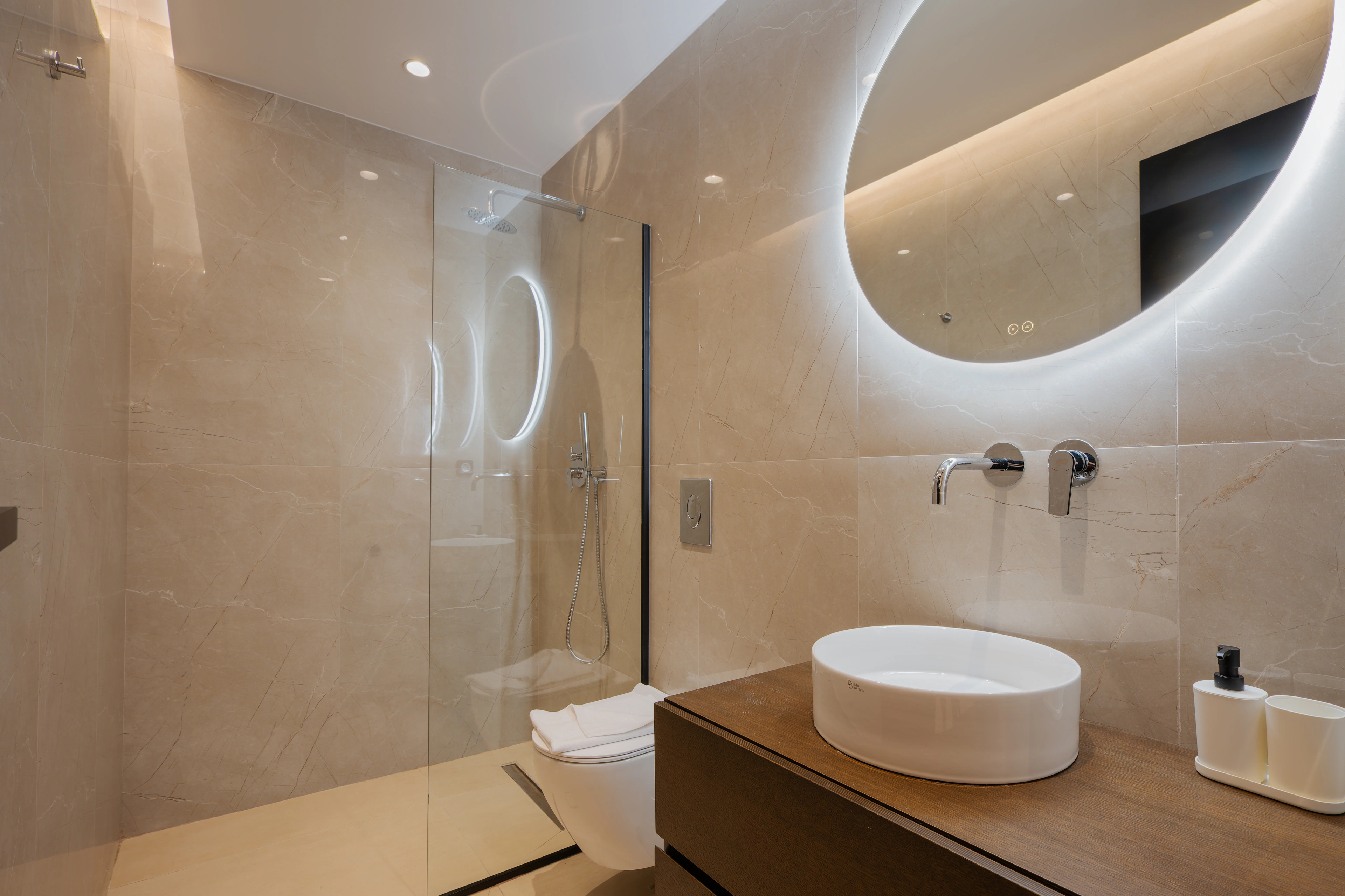 Private en-suite bathroom for Right Crete bedroom 02 with circular mirror and stone vanity