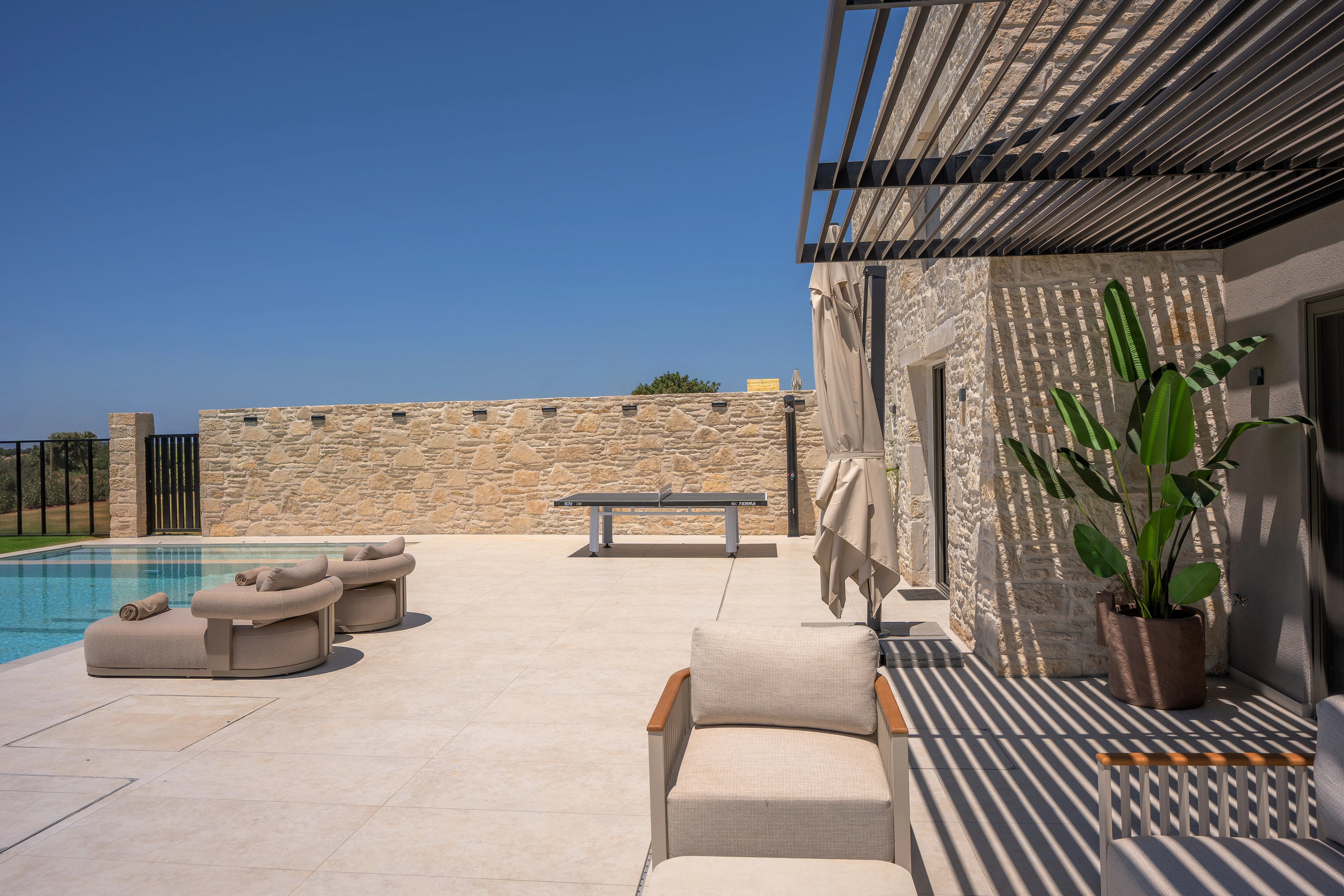 Left Crete shaded stone terrace and outdoor lounge beside the pool