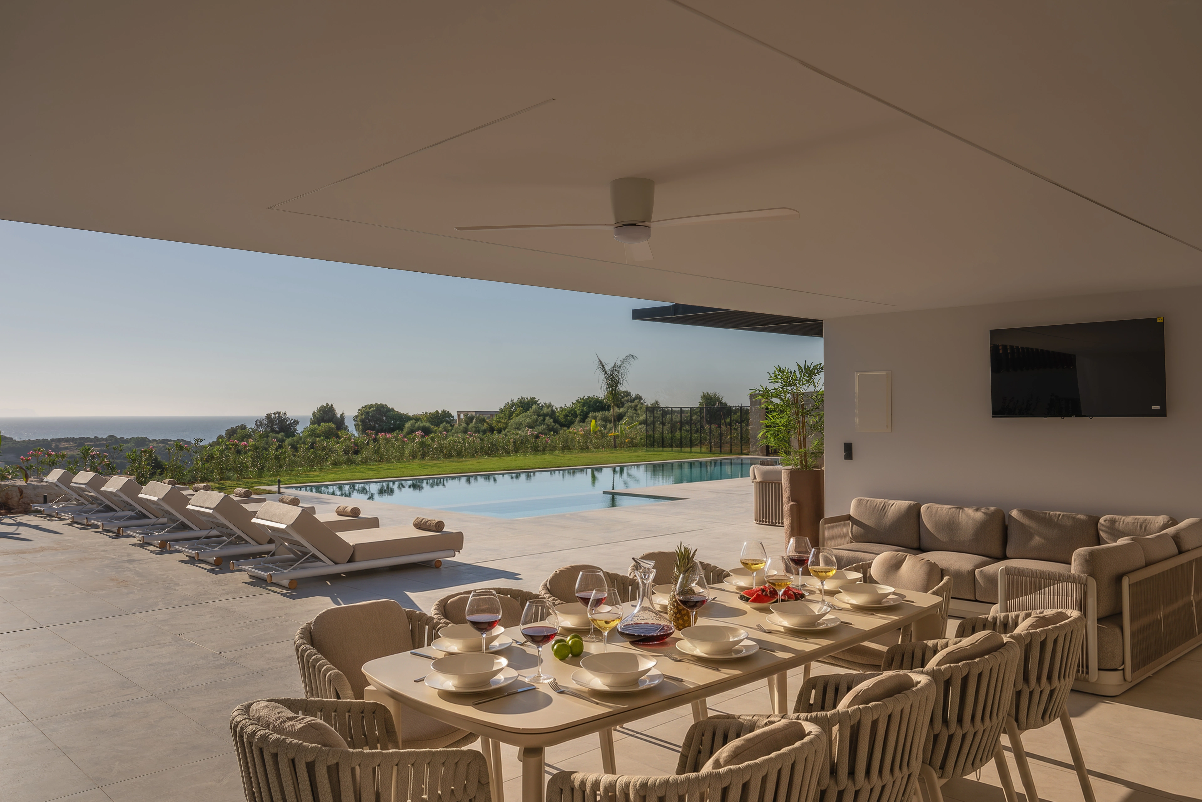 A long dining table prepared beneath Left Crete's shaded pool terrace