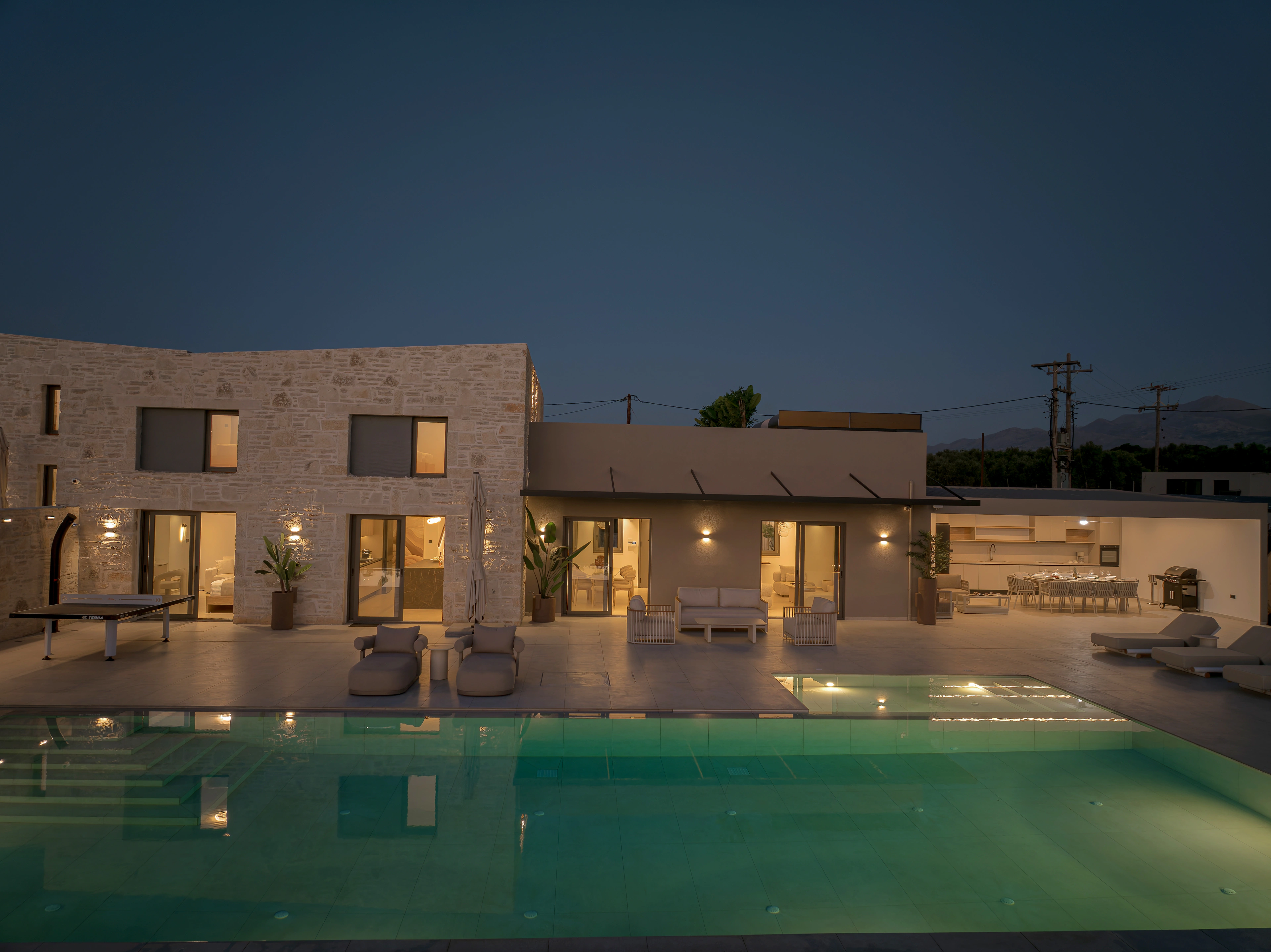 Left Crete's illuminated stone facade and pool at blue hour