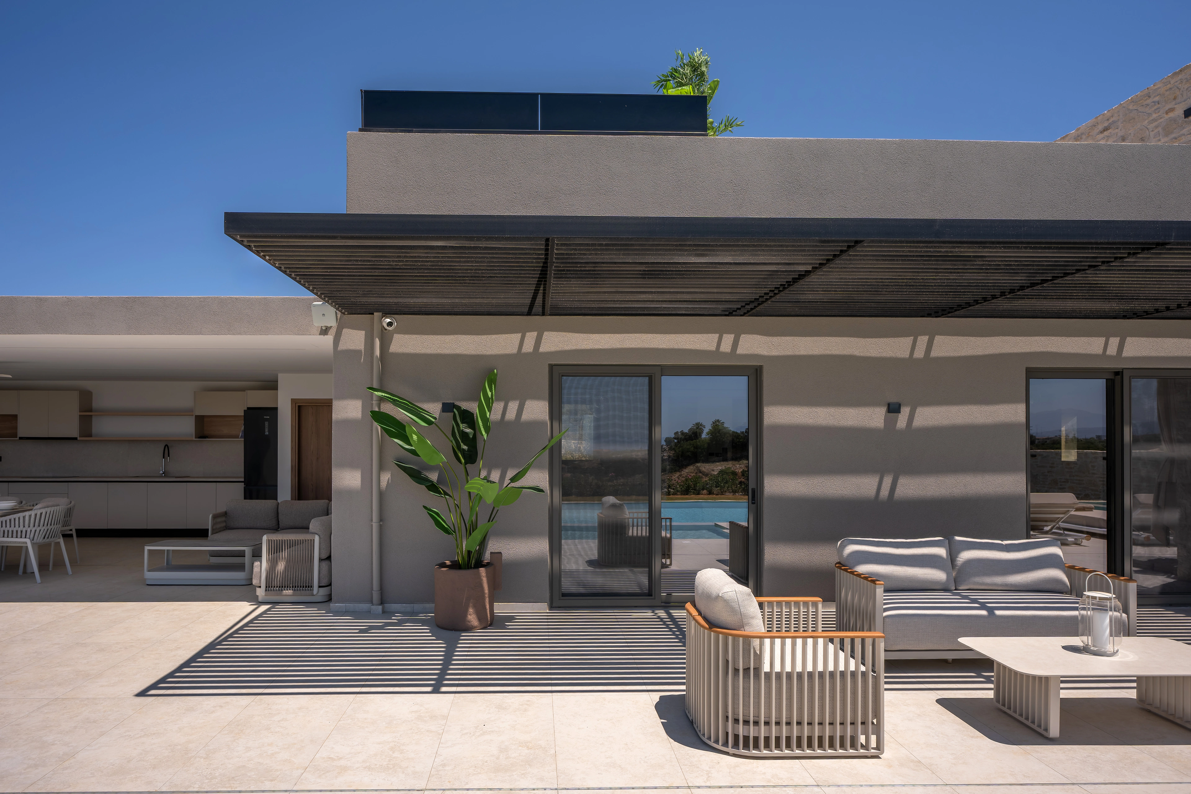 Right Crete shaded outdoor lounge and stone facade beside the pool