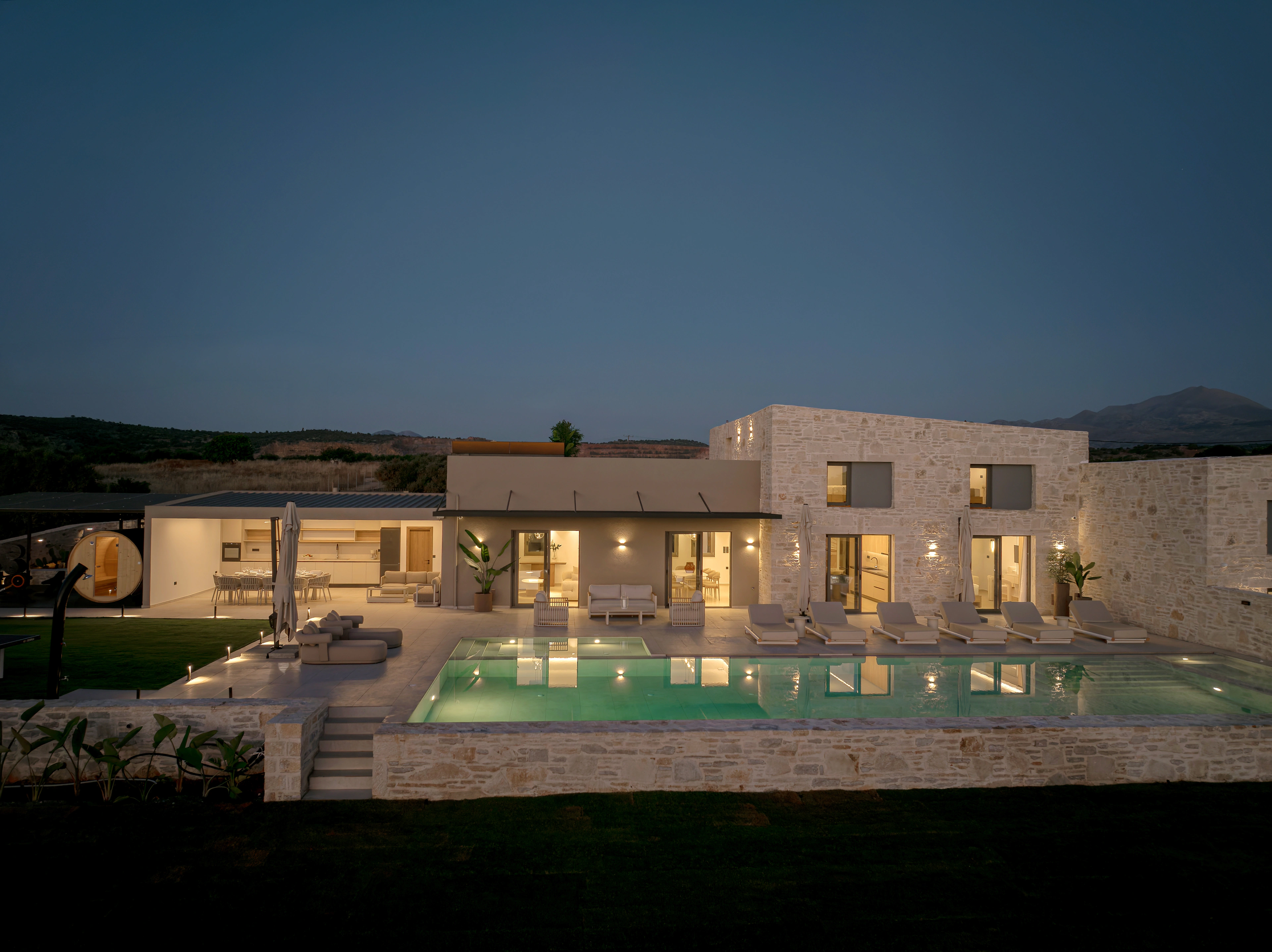 Right Crete's illuminated stone facade and pool at blue hour