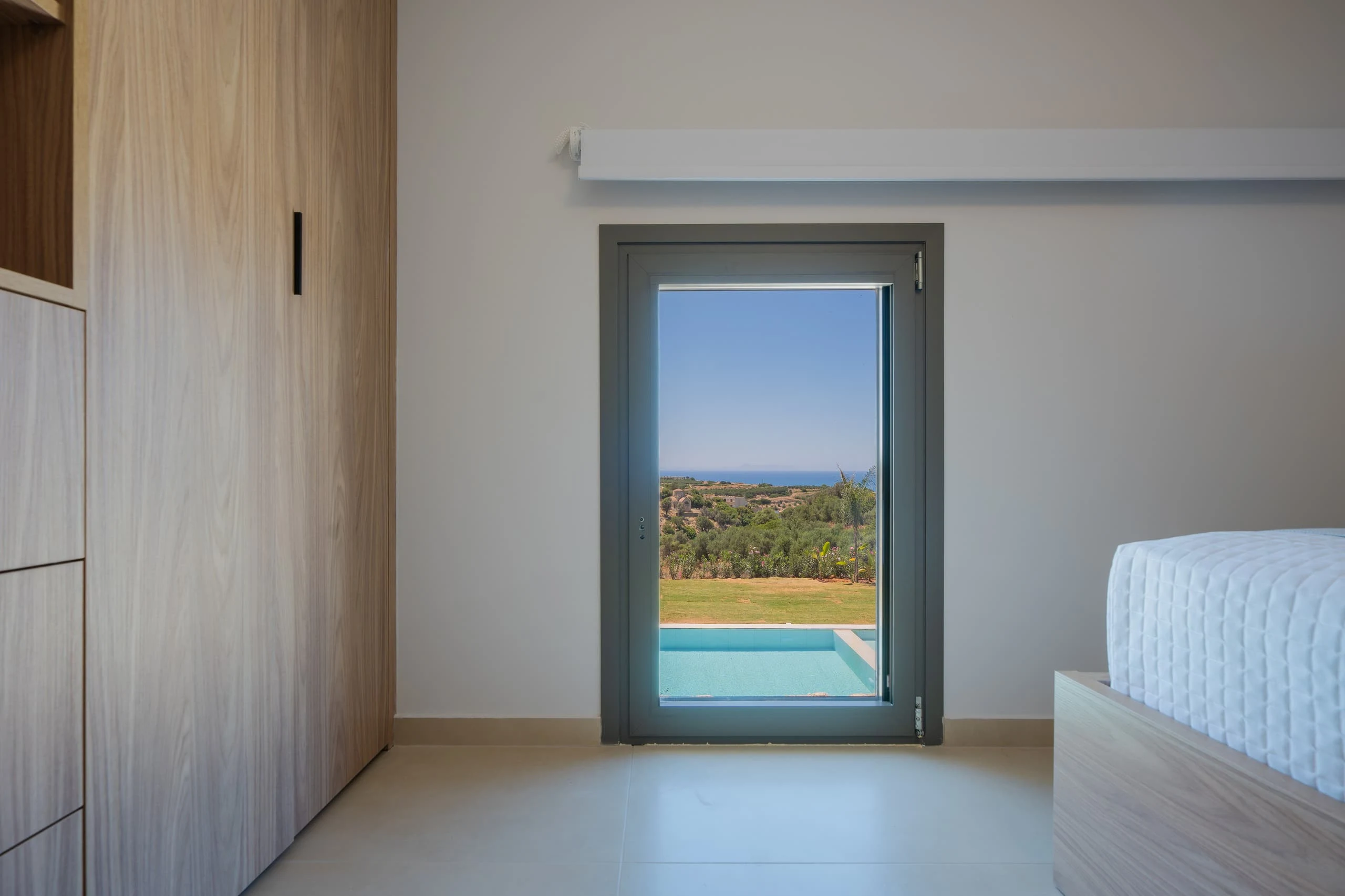 Left Crete bedroom 04 with a pool-facing window, timber wardrobe and one of the two single beds
